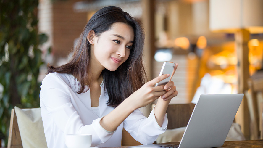 A lady is using smartphone and laptop; imaged used for HSBC Malaysia HSBC Advance Account page.